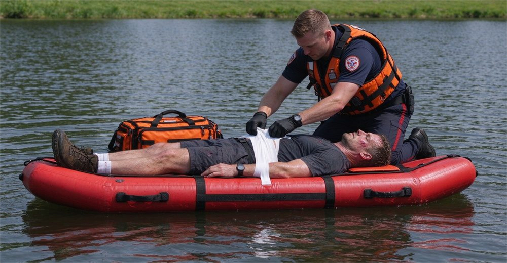Related product: emergency first aid kit real use photo with rescuer bandaging patient on foam-filled water rescue floating platform, essential flood rescue equipment for injury treatment.
