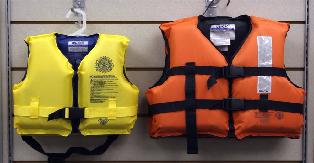 Front view of adult and child orange life jackets side by side showing family-sized personal flotation devices