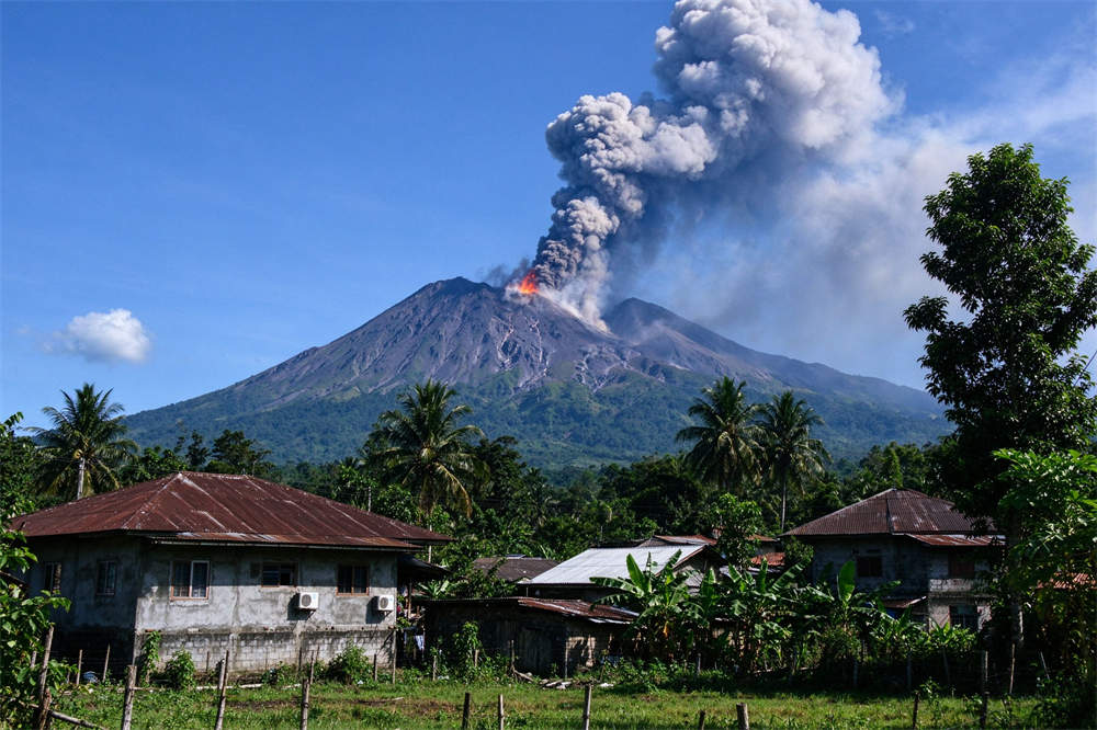 Volcano emergency kit eruption scene with black smoke billowing from crater, village in foreground, volcanic ash preparedness